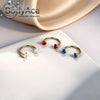 Gold-toned titanium steel nose rings featuring red, blue, and clear cubic zirconia crystals displayed on a white surface.