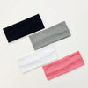 A set of four knitted hair bands in navy blue, gray, white, and pink laid diagonally on a light background.