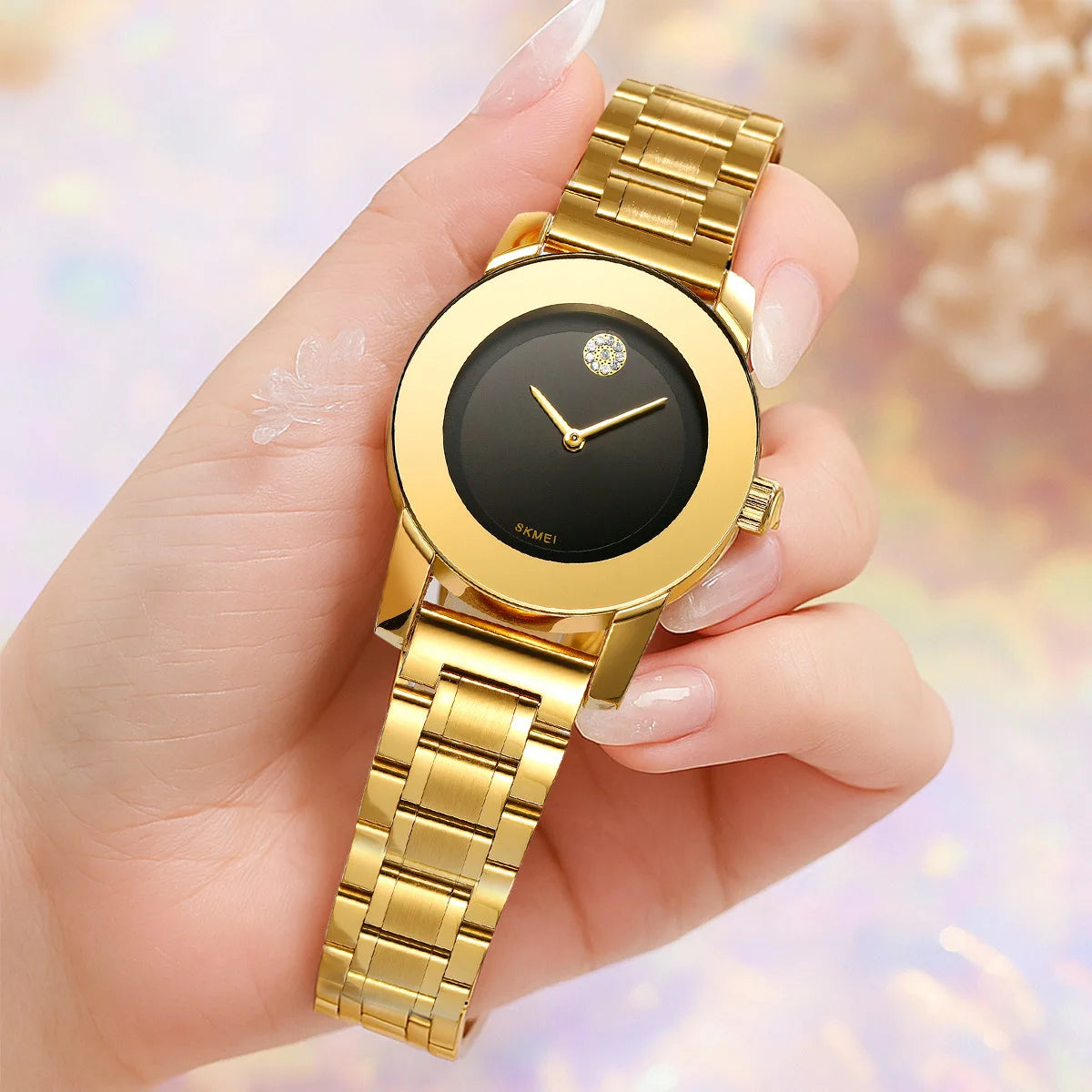 Una mano sostiene un reloj de cuarzo dorado con esfera negra y detalles dorados.