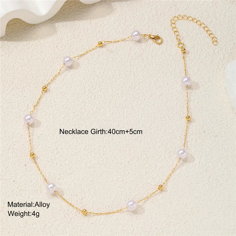 Collier délicat en alliage d'or avec de petites perles blanches, présenté sur fond clair.
