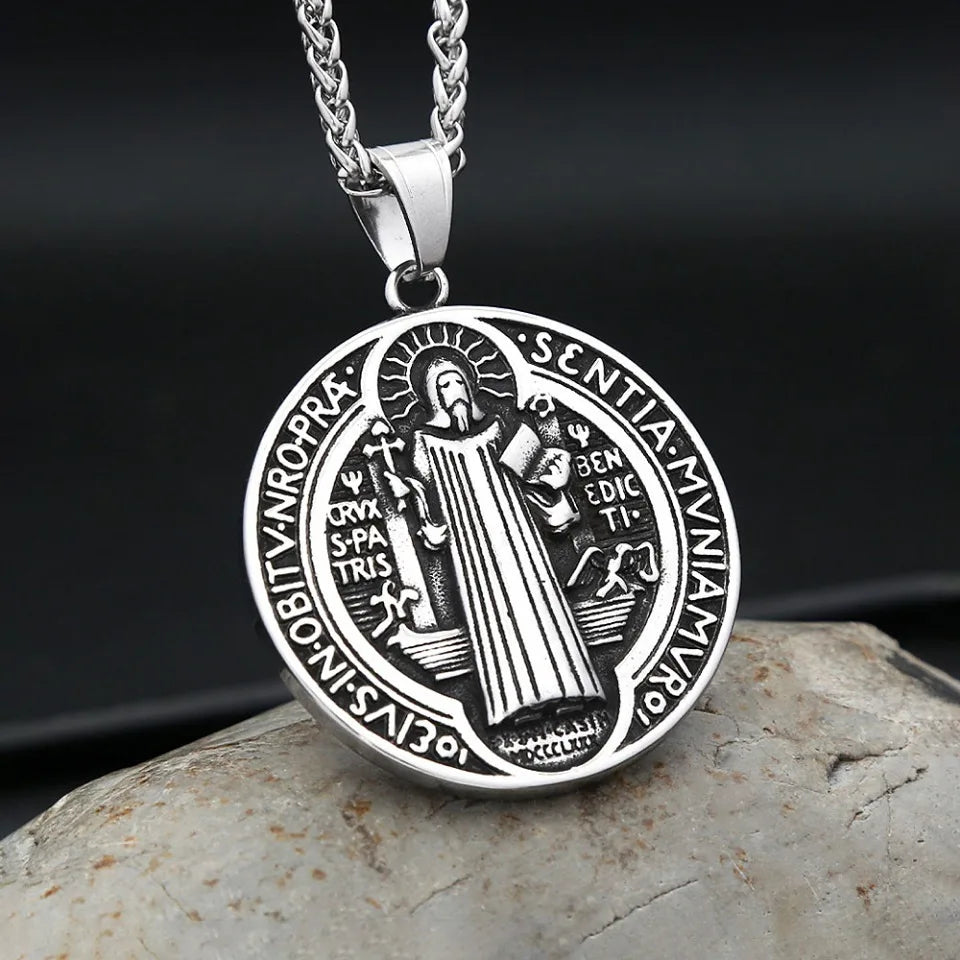 A silver pendant necklace featuring a detailed design of Saint Benedict and an exorcism theme.