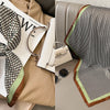 A patterned silk scarf with a floral print is displayed alongside accessories on a beige background.