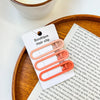 A set of vintage frosted geometry hair clips in a light orange color displayed on a wooden tray.