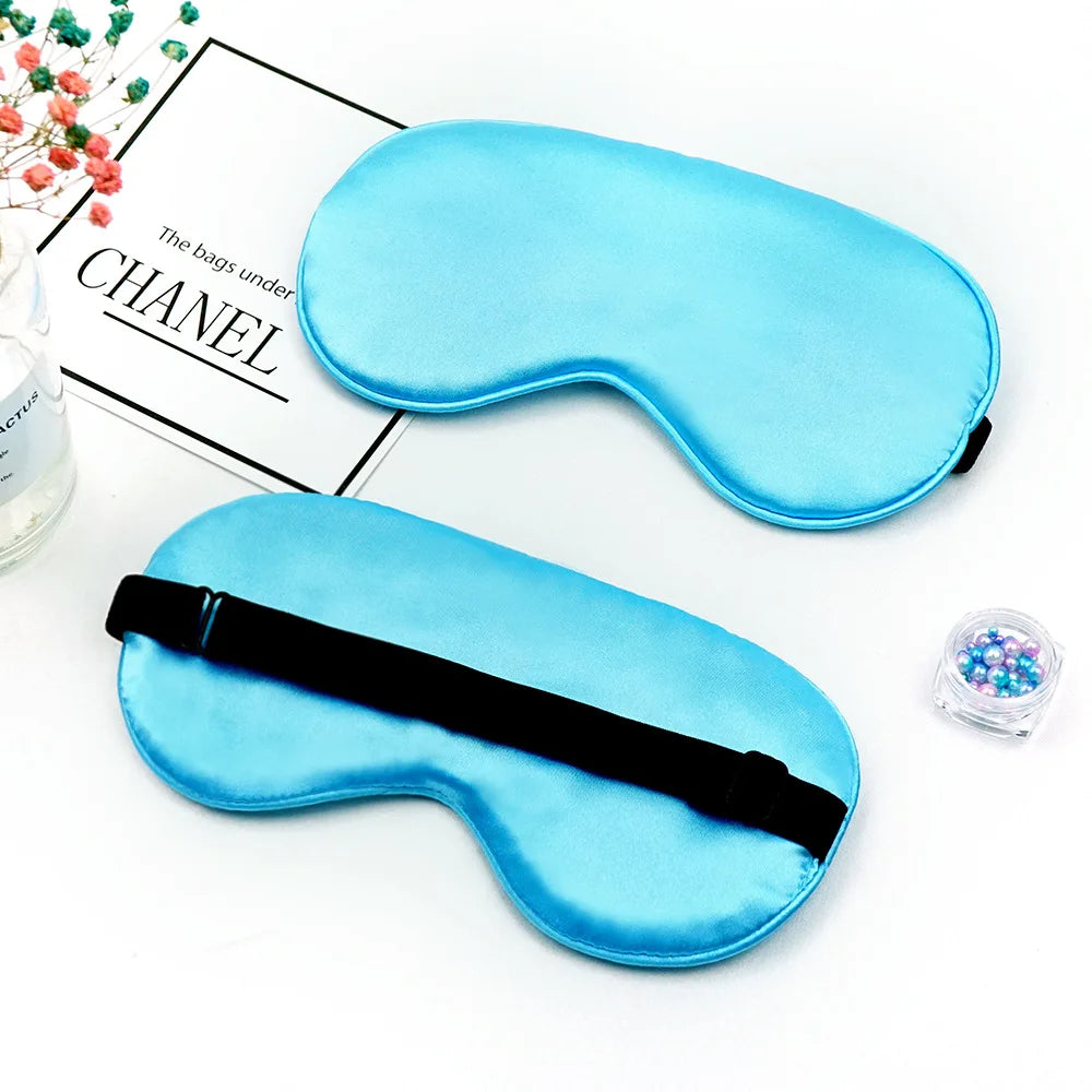 Two light blue silk sleep masks with black straps are displayed on a white background.
