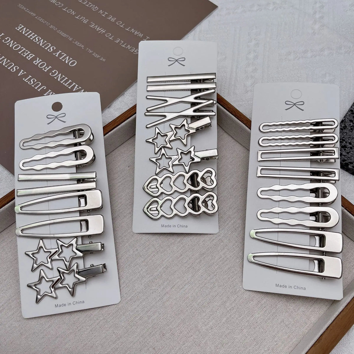 Un set de ocho pinzas para el pelo de metal plateado para flequillo y accesorios, exhibidos en una bandeja de madera.
