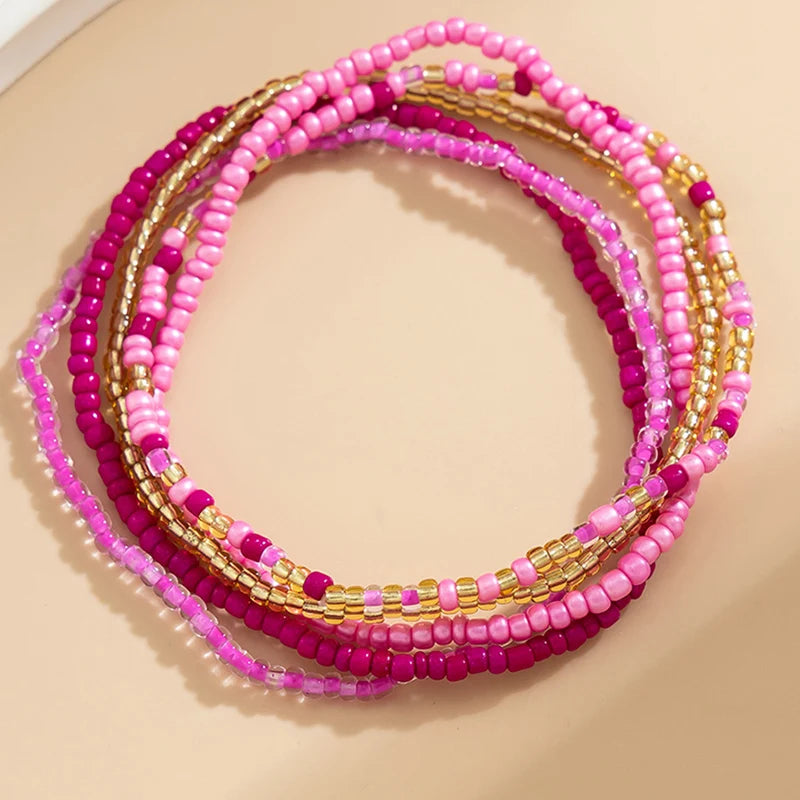 A stack of multi-layered pink and magenta beaded anklets with gold accents.