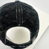 A close-up view of a black denim baseball cap with a mesh back and embroidered lettering.