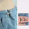 A pair of silver star-shaped decorative buttons fastened onto a denim fabric.