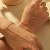 A close-up of a hand wearing a delicate gold-plated bracelet with small zircon stones.