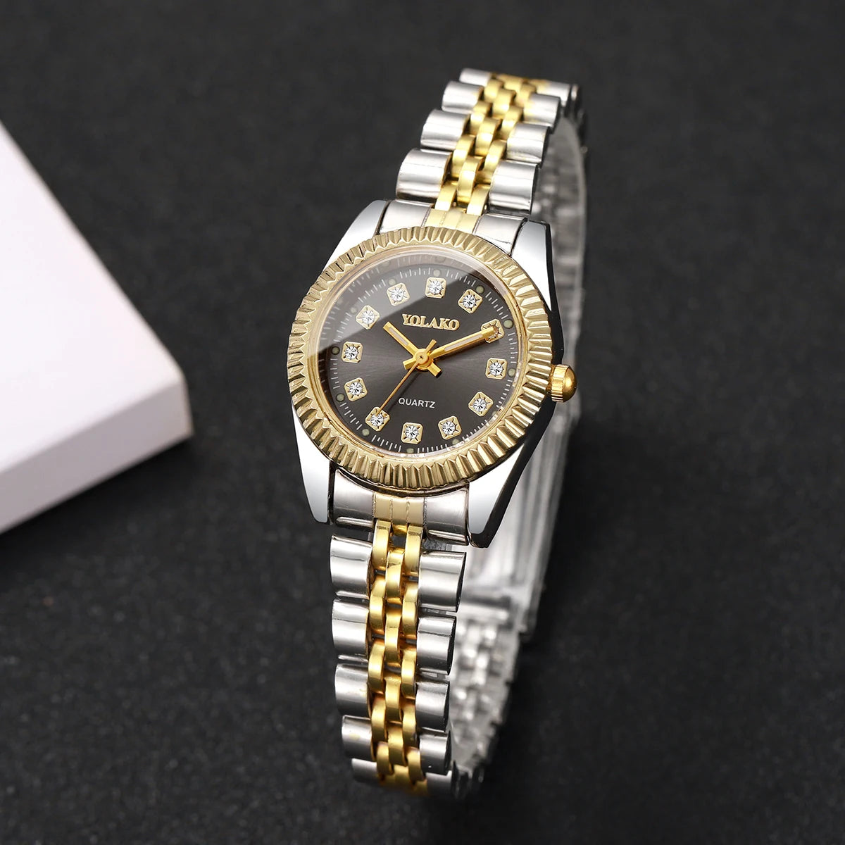 A silver and gold-toned quartz wristwatch with a textured dial and gold-toned links on a black background.