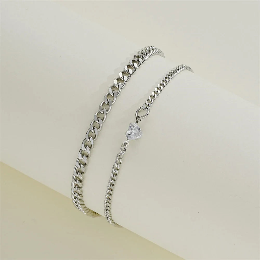 A set of two dainty stainless steel heart link bracelets for couples displayed against a light background.