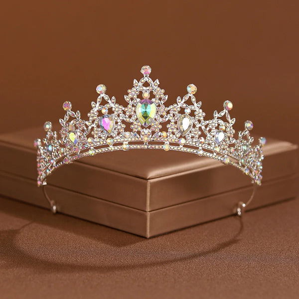 An elegant crystal baroque bridal tiara headpiece displayed on a box against a brown background.