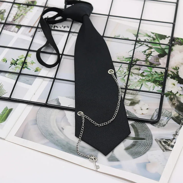 A black classic chain necktie is displayed against a grid background with floral imagery.