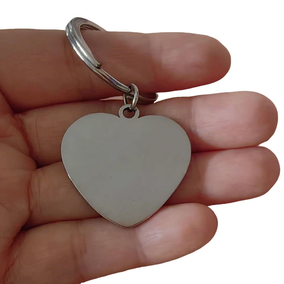 Una cadena con forma de corazón plateado sostenida en la mano de una persona.