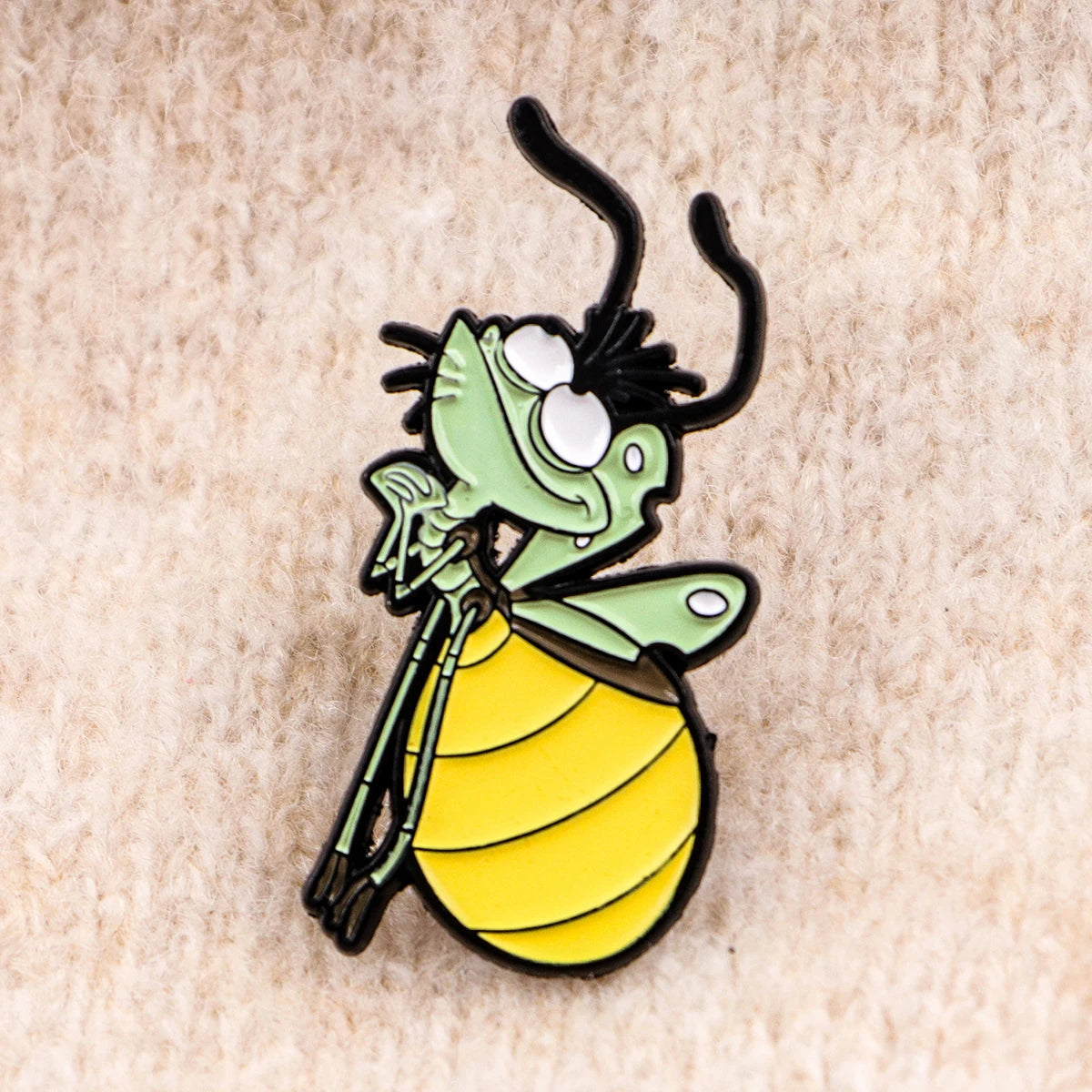 A cute firefly enamel pin featuring a frog-like character with green skin and yellow stripes.