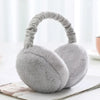 A pair of soft gray plush fur ear warmers or earmuffs resting on a white surface.