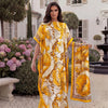 A woman models a yellow and brown tropical floral leopard print abaya scarf outdoors in front of a white building.