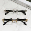 Pair of vintage Y2K frameless glasses with black frames and gold accents displayed on a white marble surface.