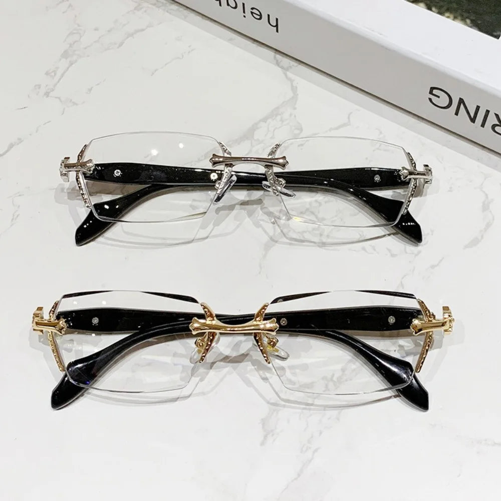 Pair of vintage Y2K frameless glasses with black frames and gold accents displayed on a white marble surface.