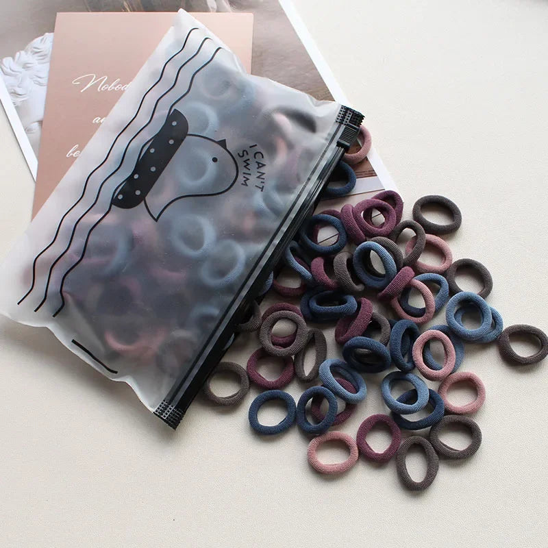 A clear plastic pouch filled with various colored elastic hair bands for ponytail holders.