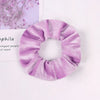A close-up of a lavender velvet scrunchie, showing its texture and gathered fabric.