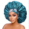 A model wears an extra large satin sleep bonnet in teal green with a floral pattern.