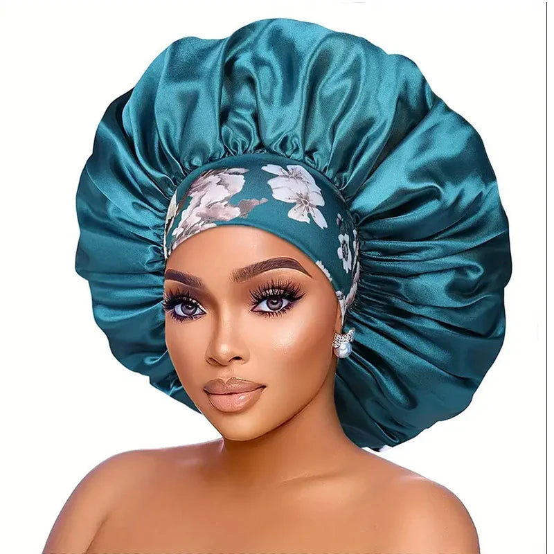 A model wears an extra large satin sleep bonnet in teal green with a floral pattern.