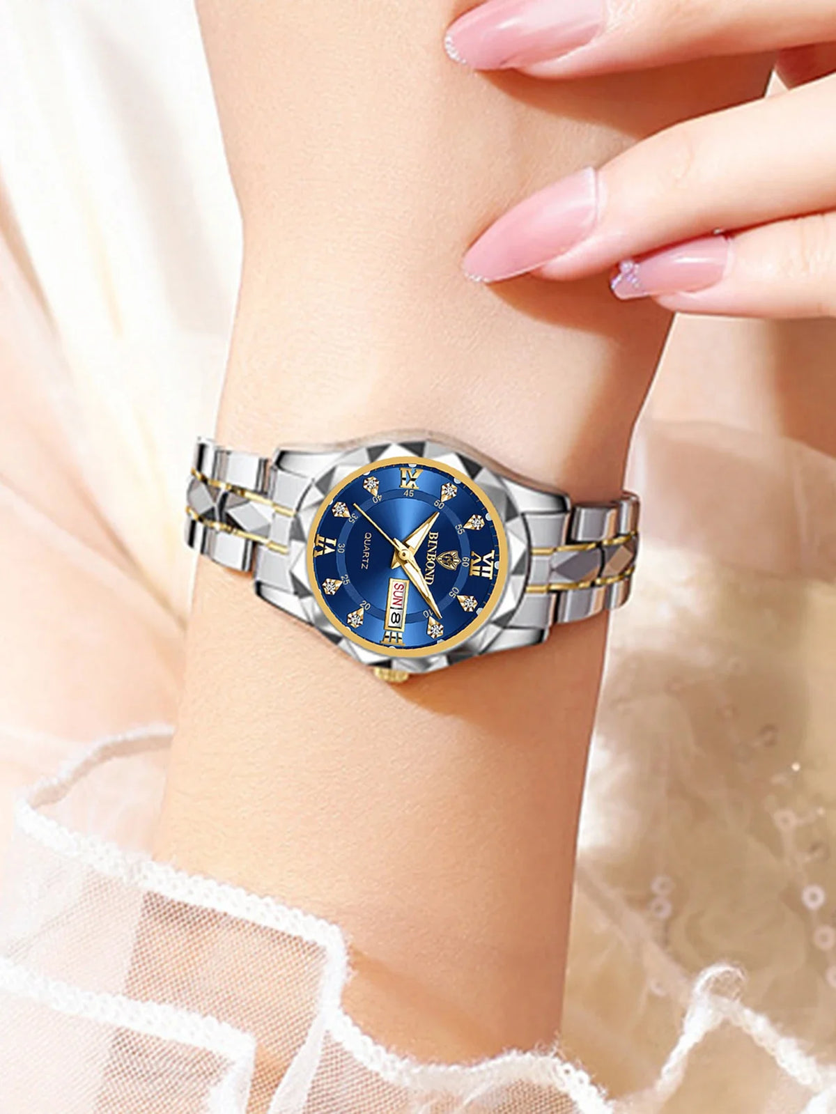 A close-up of a stainless steel couple watch with blue dial and gold accents worn on a wrist.