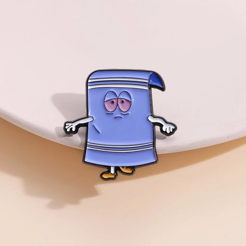 A cartoon enamel pin of a blue, slightly grumpy-looking figure wearing a striped tunic.
