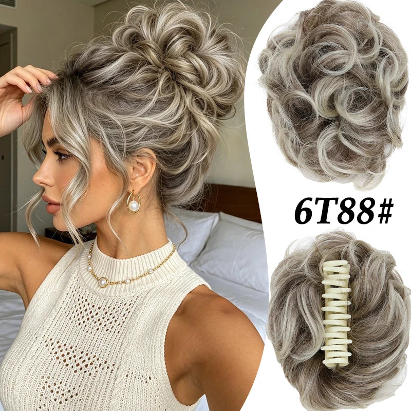 A woman shows off a voluminous curly messy bun hairstyle with silver-gray hair and gold jewelry.