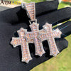 Rapproché d'un pendentif croix serti de glace tenu dans une main contre un fond vert flou.