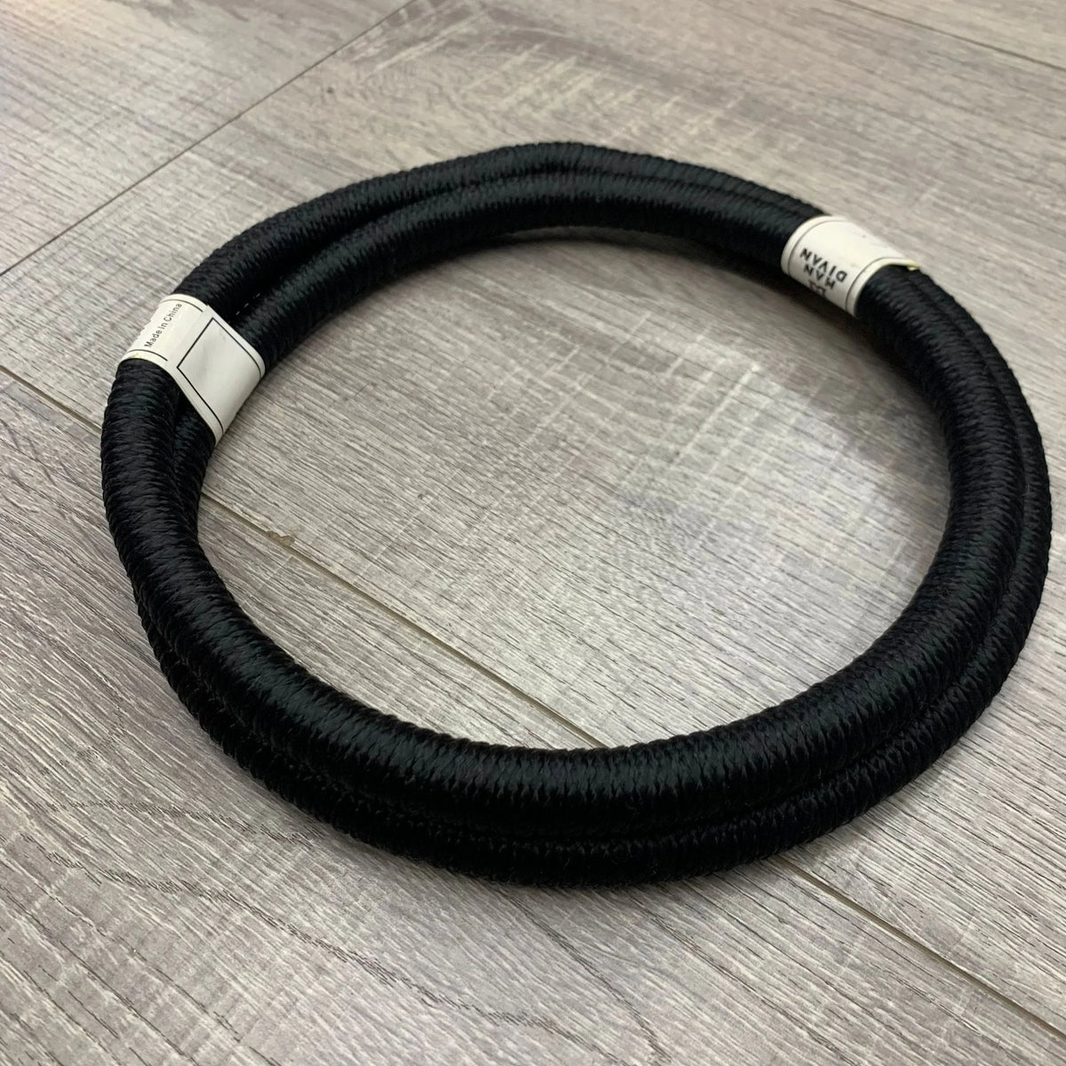 Pañuelo táctico negro con cuerda de agal enrollada sobre una superficie de madera.