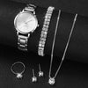 A silver quartz wristwatch, a diamond bracelet, and several diamond necklaces displayed on a black surface.