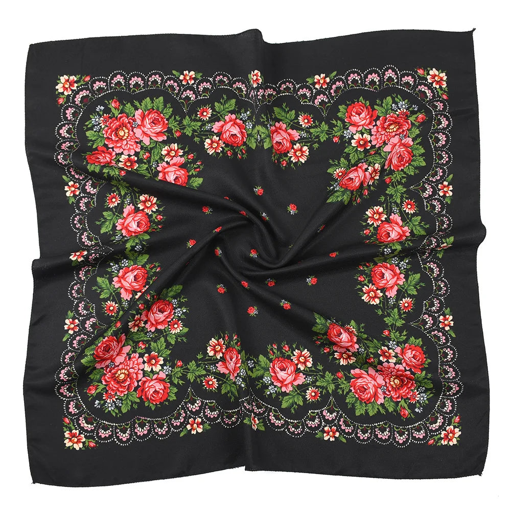A black square scarf featuring a luxury floral print with red and pink roses and greenery.