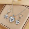 Silver heart necklace and earring set displayed in a light brown box.