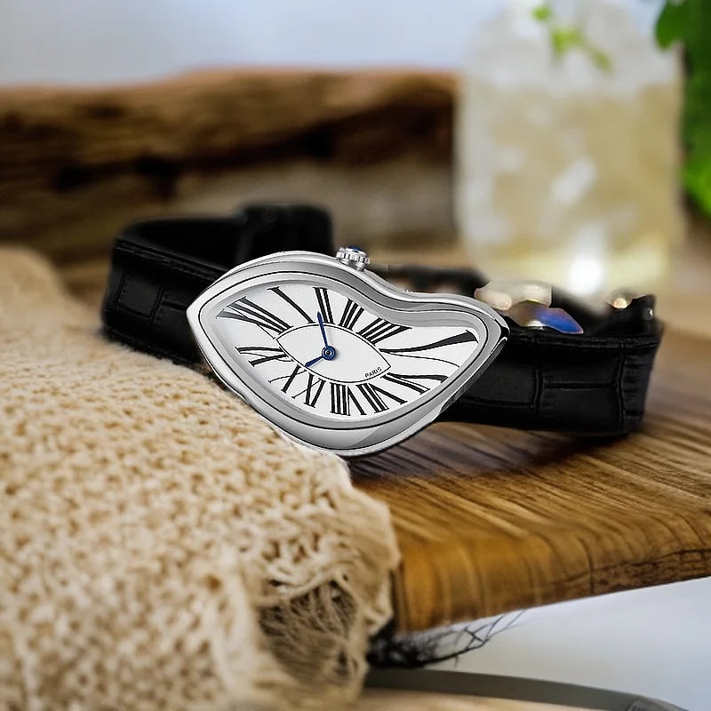 A silver fashion quartz wristwatch with a Roman dial and black leather strap resting on a wooden surface.
