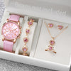 A pink quartz wristwatch with a rose gold band and pink leather strap is displayed in an open box alongside jewelry.
