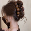A close-up of a woman's dark brown hair styled in an elegant updo with a tortoiseshell acrylic pearl hair claw clip.