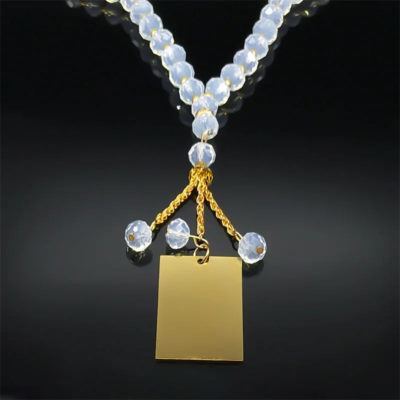 A gold-colored pendant necklace featuring clear round beads and a square gold charm.