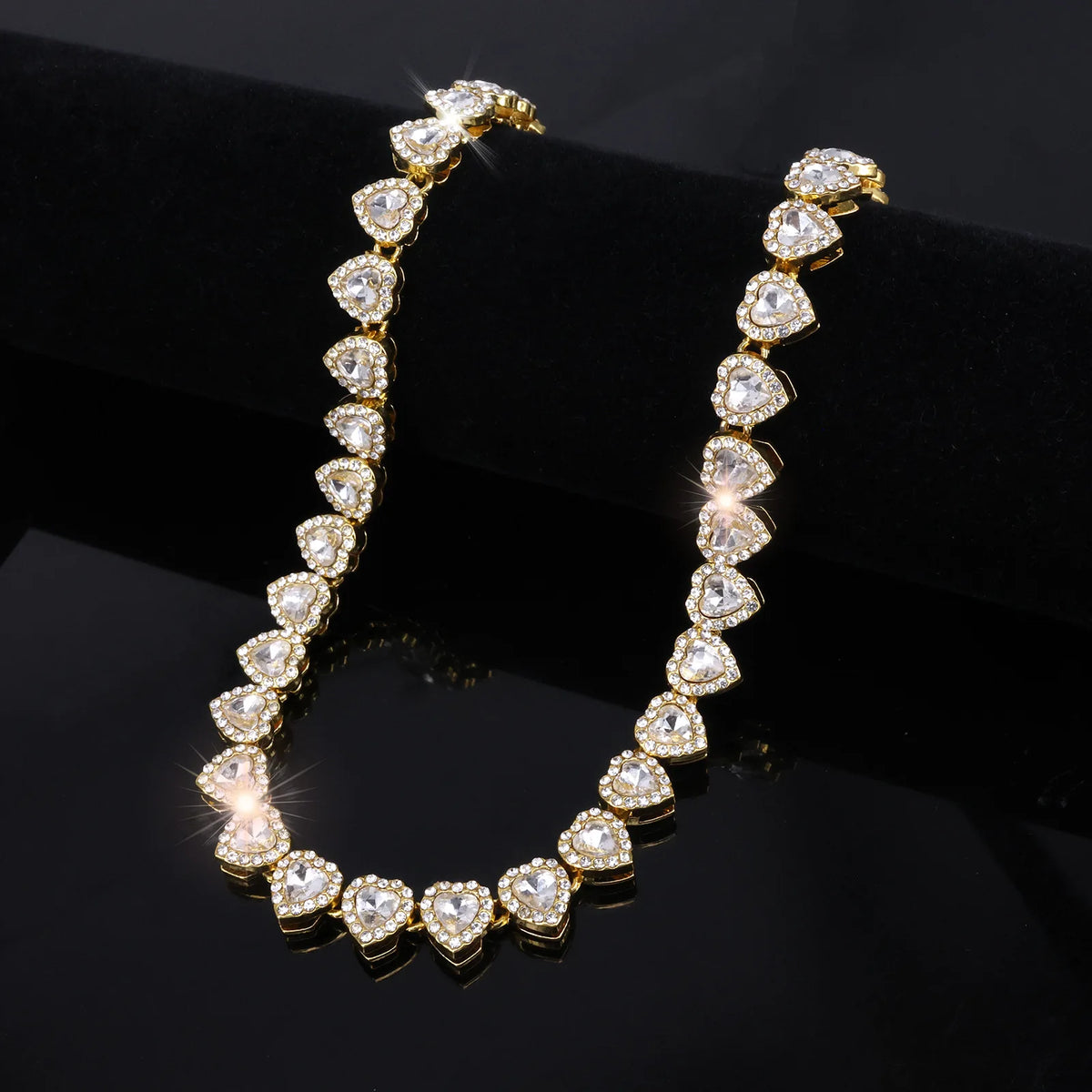 A close-up shot of a sparkling heart rhinestone necklace and bracelet set on a black surface.