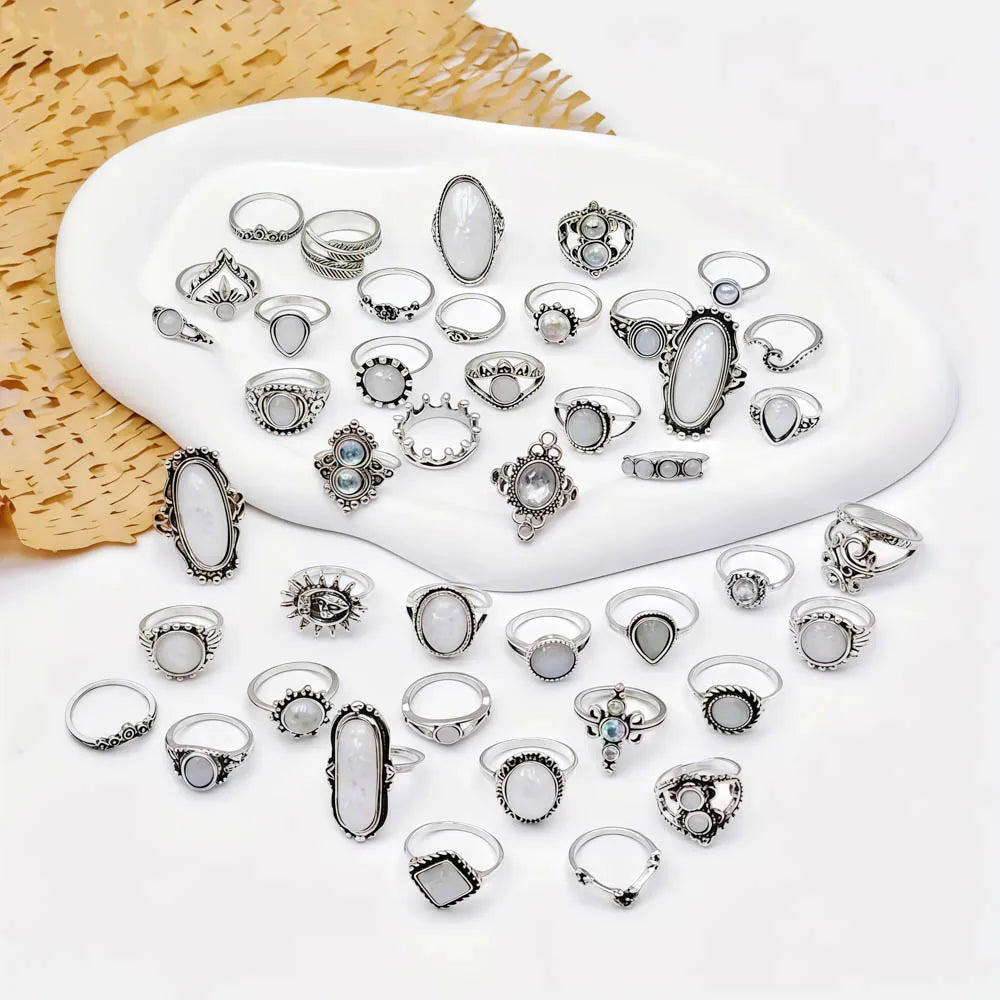 A collection of silver and gemstone charm rings displayed on a white oval dish.