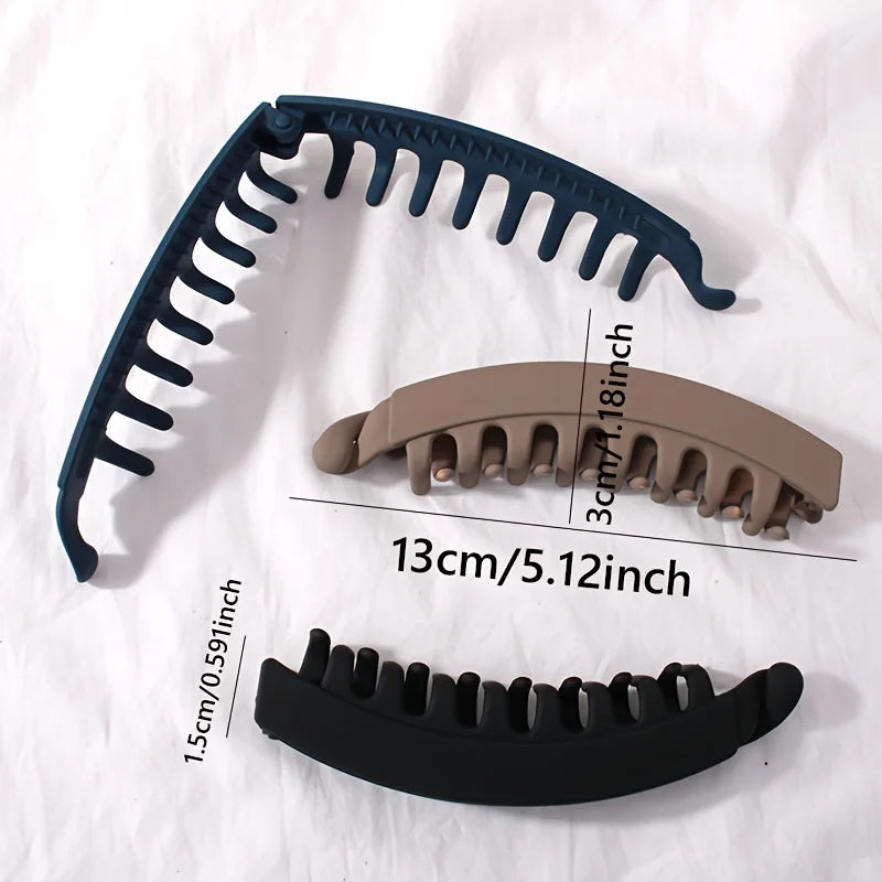 A set of three black and tan banana-shaped hair clips shown in various angles.