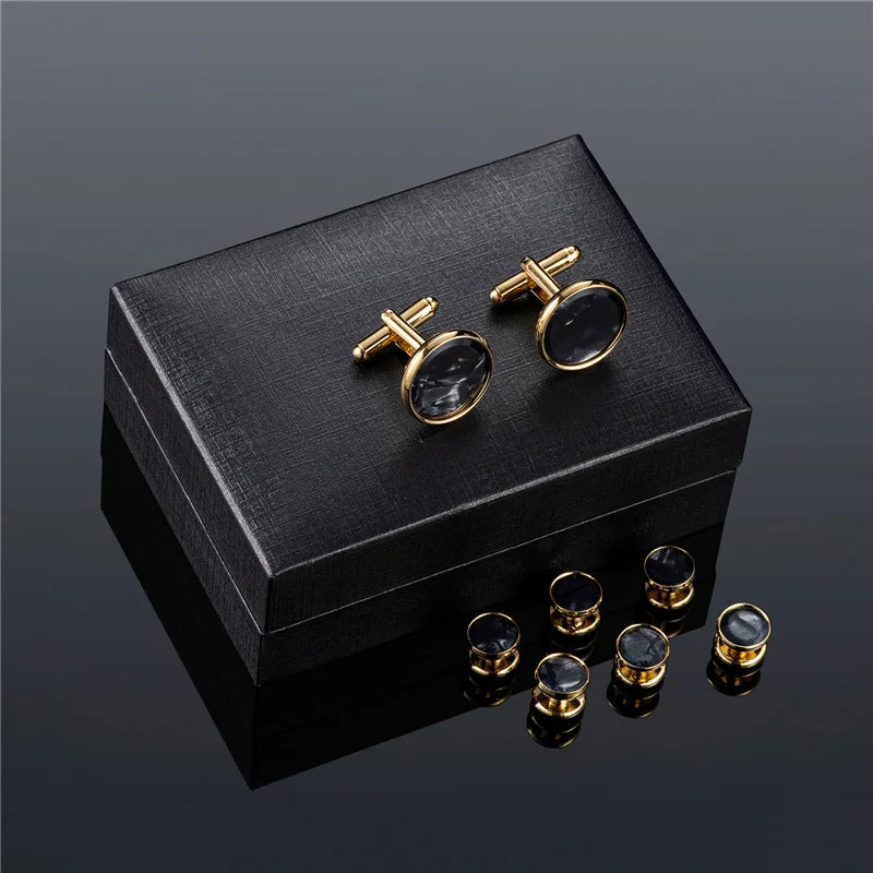 Une boîte noire contenant un élégant ensemble de boutons de manchette et de pinces à cravate dorés avec des pierres sombres.