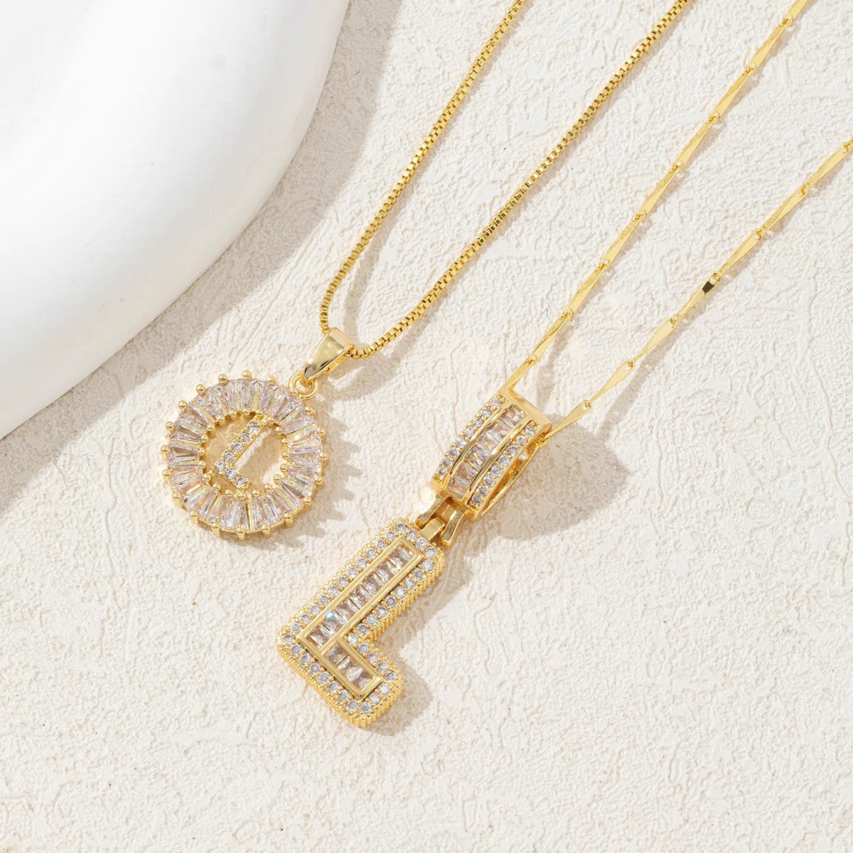 Gold-toned necklace set featuring CZ crystal pendants shaped like the letter D and E.
