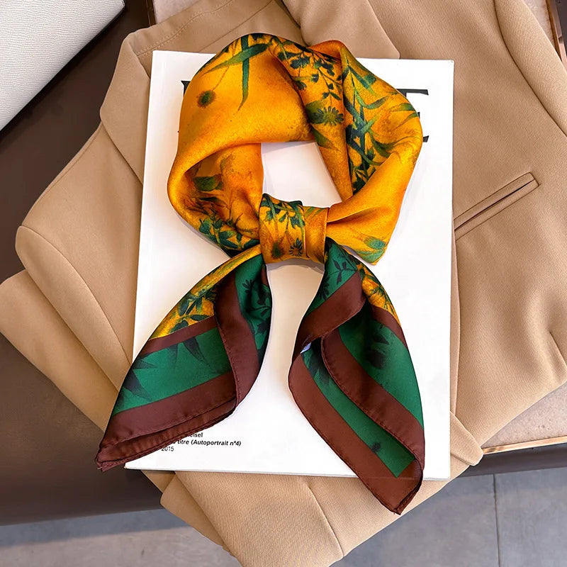 A yellow silk scarf tied in a bow with green and brown stripes, displayed on a white card against a beige blazer.