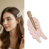 A close-up of a woman wearing pink angel wing hair clips and barrettes in her dark brown hair.