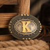 A vintage western belt buckle with an ornate gold design set in a dark metal frame.