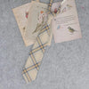 A stack of Japanese plaid neck ties featuring illustrations of birds and text on a light background.