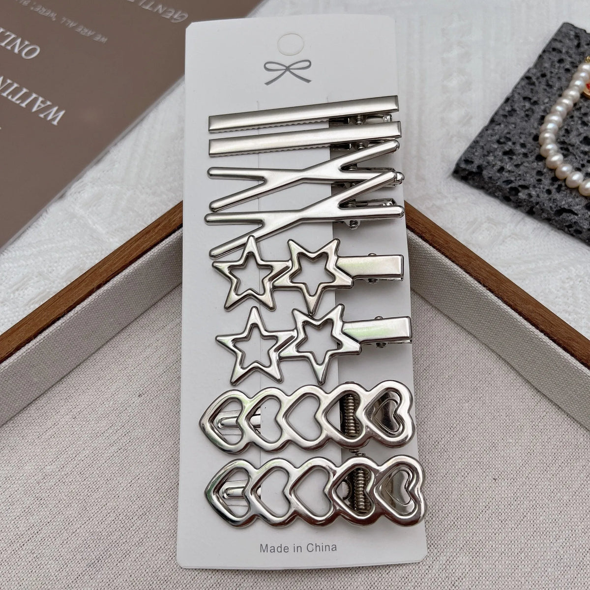 Un set de ocho clips de pelo y accesorios metálicos para flequillo y cabello, empaquetado en una tarjeta blanca.