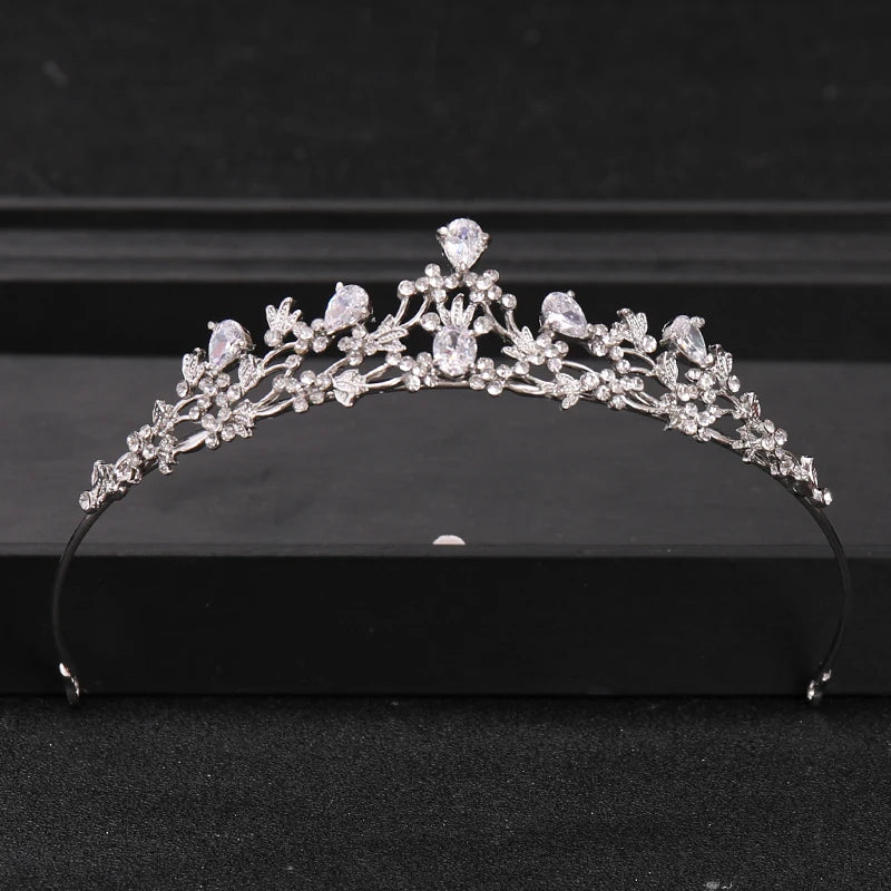 A silver crystal rhinestone bridal tiara headpiece displayed on a dark surface.